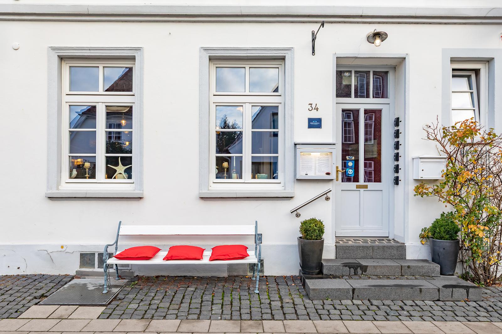Eingang des Hotels mit weißer Bank und roten Kissen
